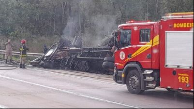 Carreta tomba, pega fogo e motorista morre preso 